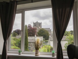 A window with curtains, a view of a castle, and two small potted plants on the windowsill.