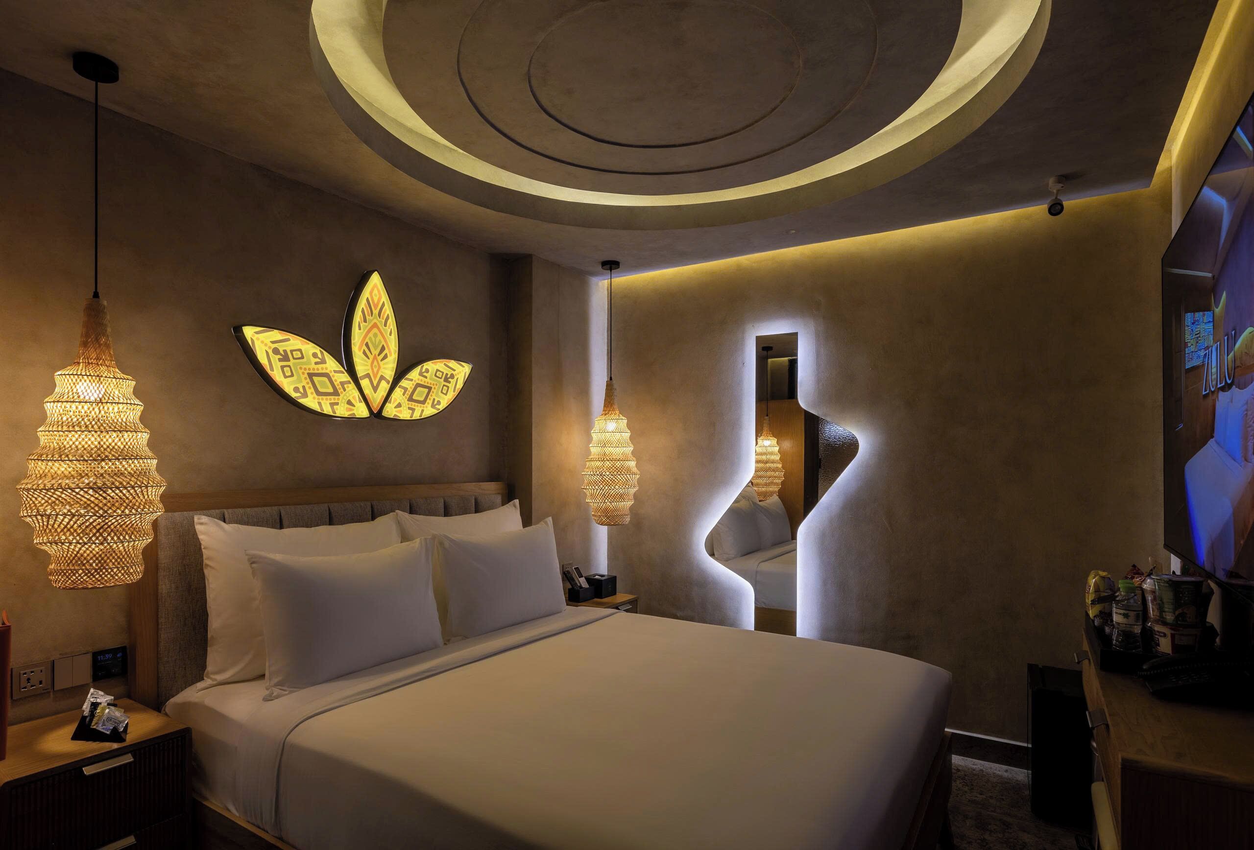 A modern hotel room with a large bed, two bedside lamps, a unique wall design, and a television.