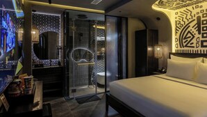 A modern hotel room with a bed, a TV, a bathroom with a glass shower enclosure, and a decorative wall. - PYNT HOTEL 8 (Ho Chi Minh City)