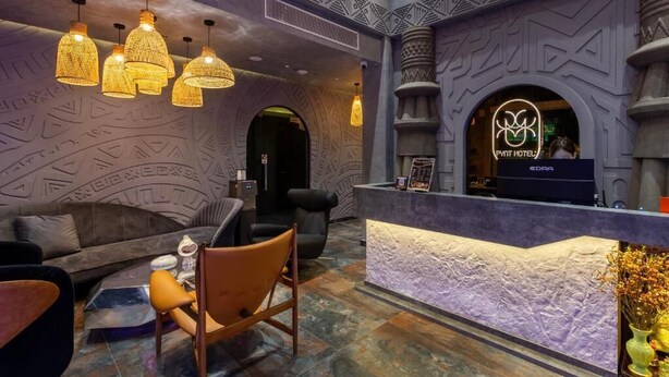 A hotel lobby with a reception desk, seating area, and decorative wall patterns. - PYNT HOTEL 8 (Ho Chi Minh City)