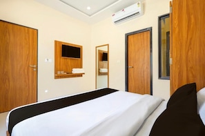 Une chambre d’hôtel équipée d’un lit, d’une armoire en bois, d’un miroir et d’un appareil de climatisation.