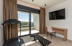Ein modernes Hotelzimmer mit Laufband, Schreibtisch, Stuhl und einem großen Fenster mit Blick.