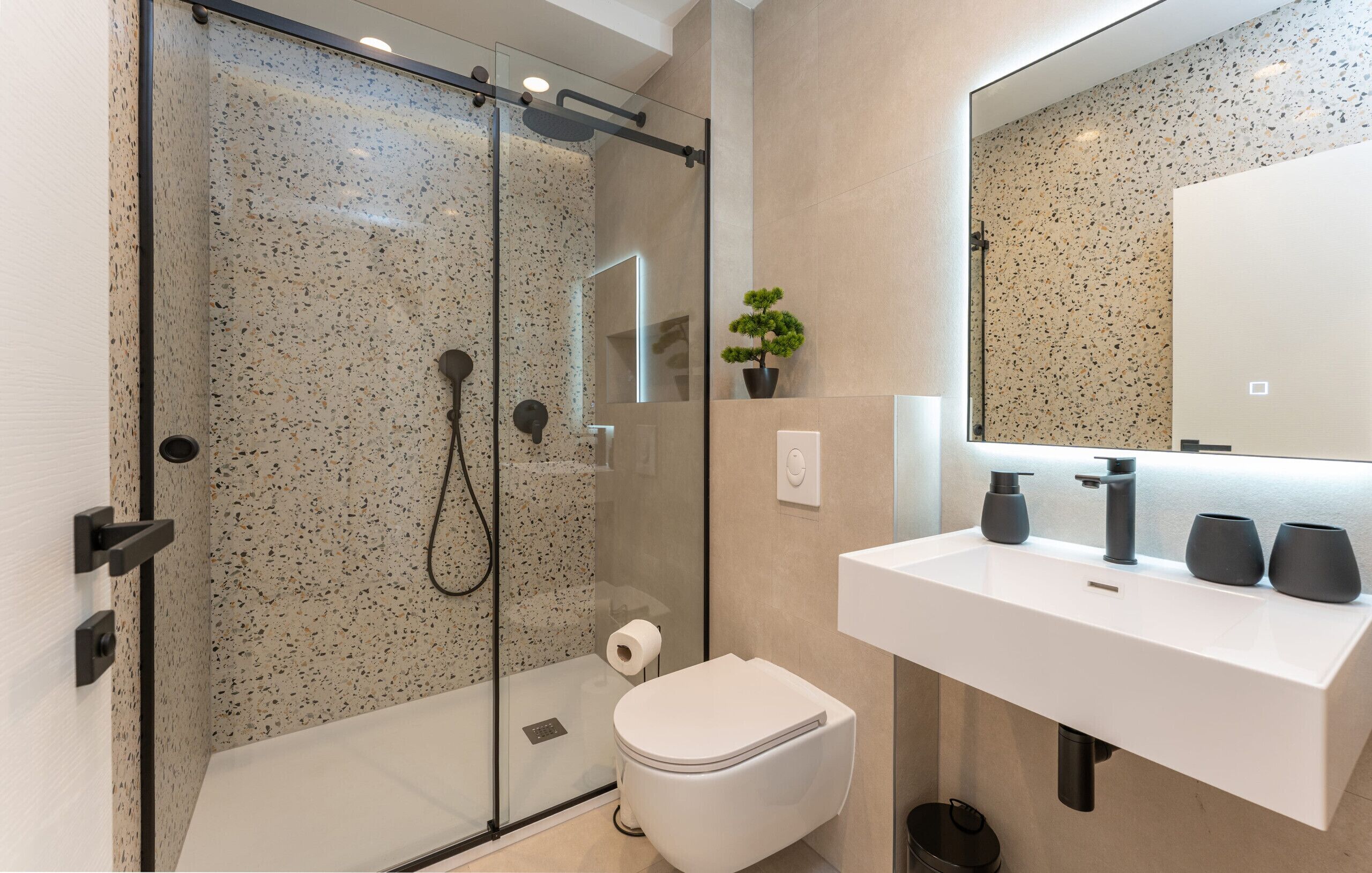A modern bathroom with a glass-enclosed shower, a white sink, and a mirror.