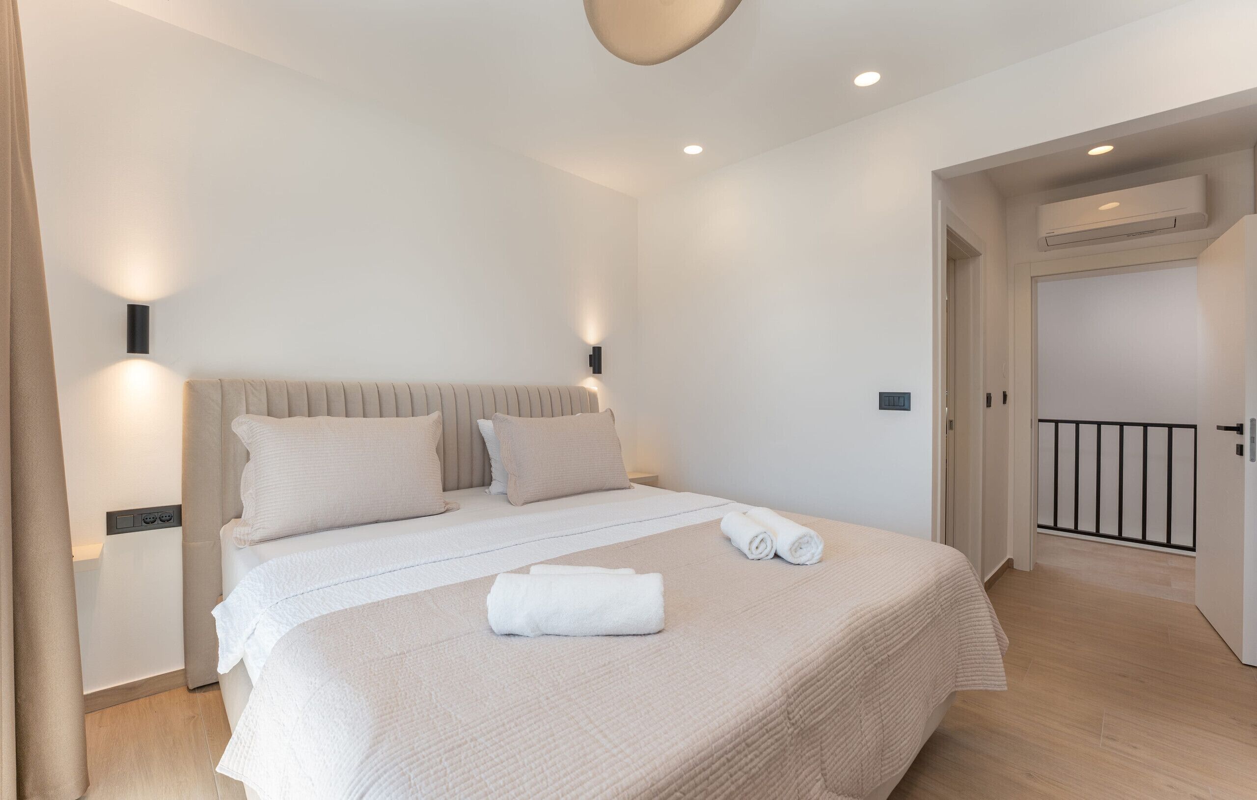 Une chambre moderne avec un grand lit, des lampes de chevet et une vue sur un balcon.