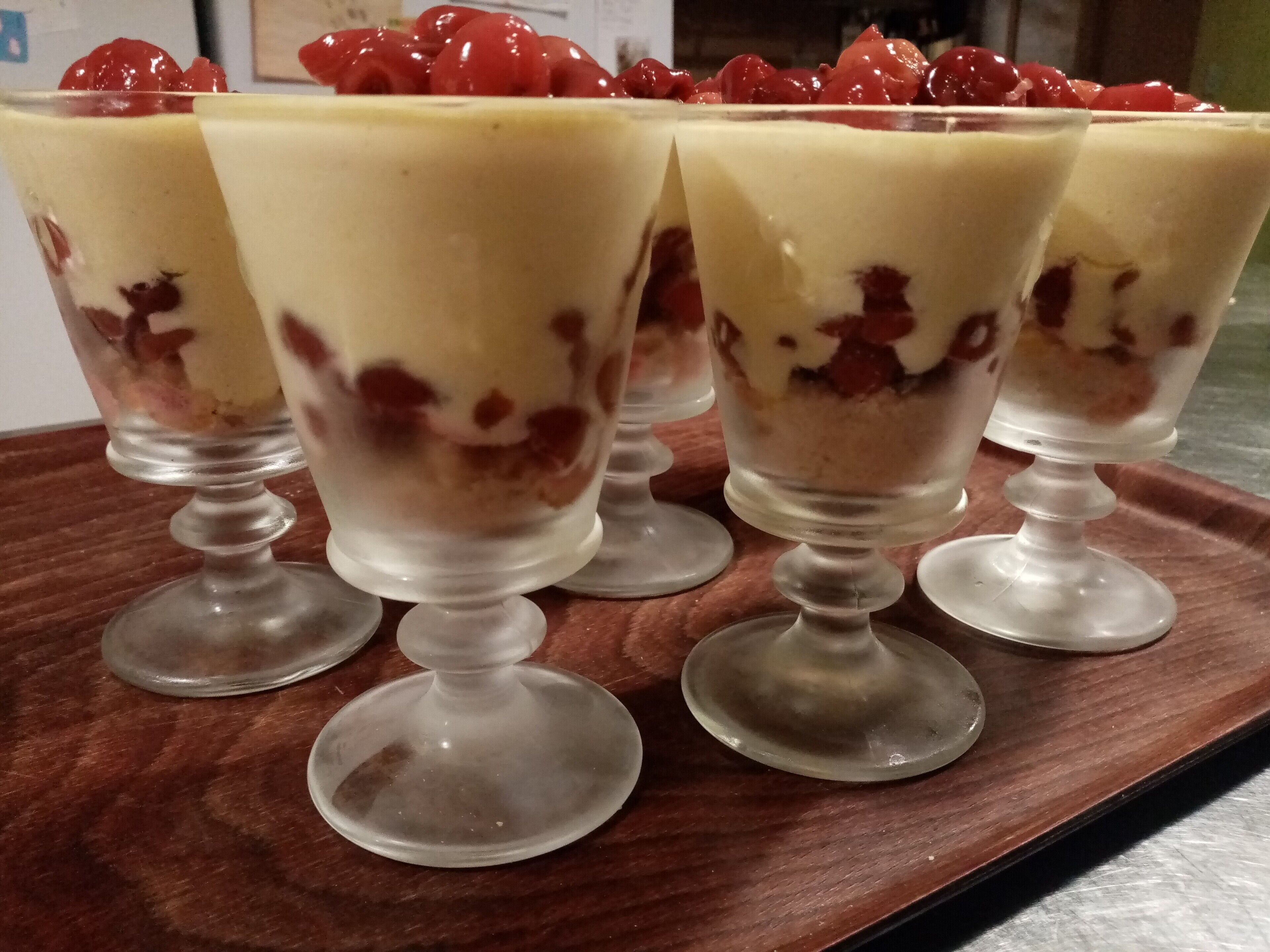 Four dessert glasses on a wooden tray.