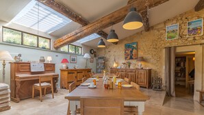 A spacious kitchen with wooden cabinets, a dining table set for four, and a piano. - Ma maison de loin - Saturnin Room (Apt)