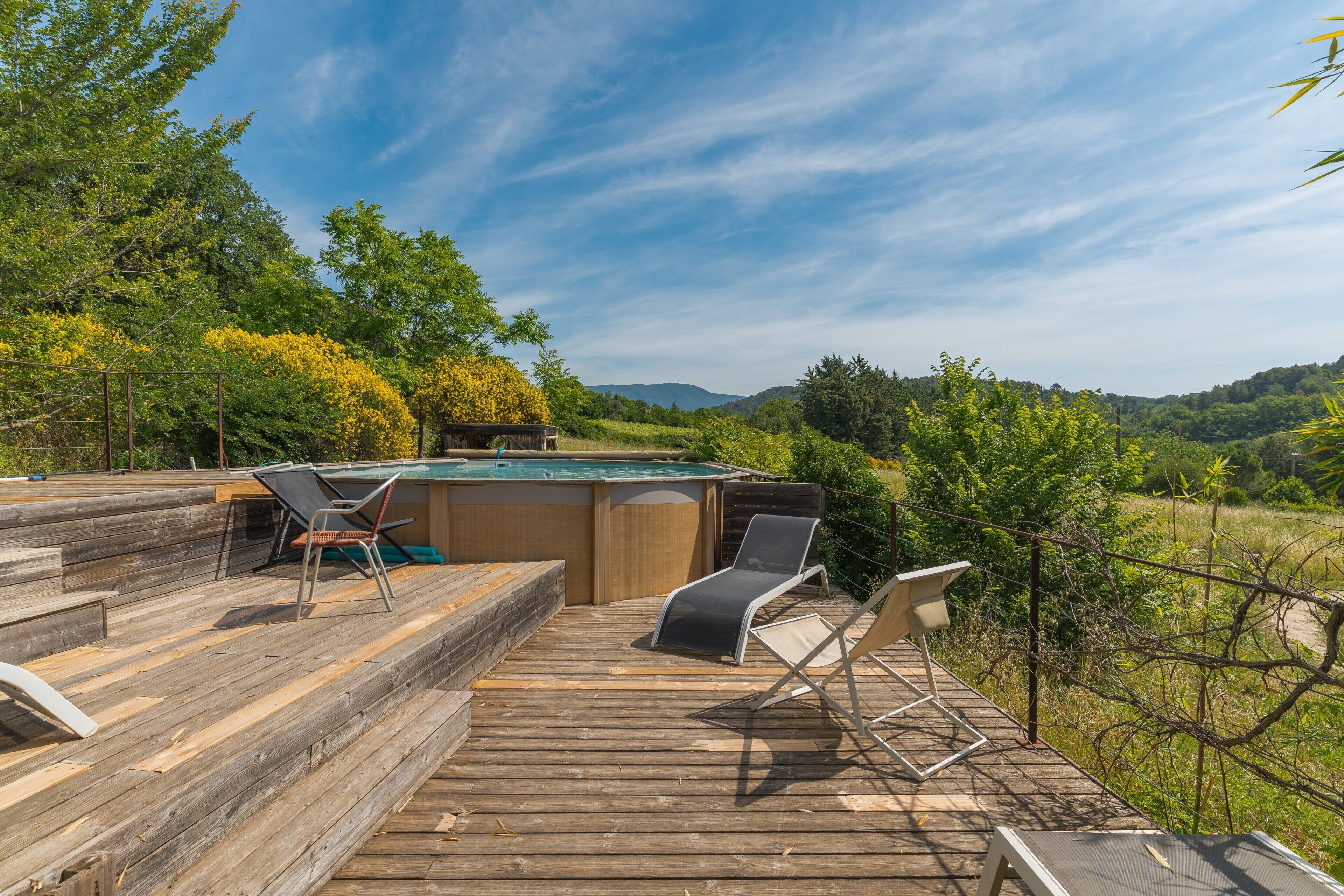 Une terrasse en bois avec une table de billard, deux fauteuils et un jacuzzi.