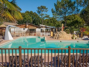 A pool area with lounge chairs, a lifeguard tower, and a building with a thatched roof. - Mobile home, pets welcome - 4 guests (Grayan-et-l'Hôpital)