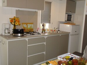 A compact kitchen with a gas stove, a coffee maker, a microwave, and a refrigerator. - Mobile home, pets welcome - 4 guests (Grayan-et-l'Hôpital)