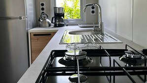 Cozinha moderna com fogão a gás, eletrodomésticos de aço inoxidável, janela com vista para o verde e uma pia.