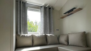 Uma sala de estar moderna com um sofá, uma mesa de centro de madeira e uma janela com cortinas.