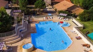 Piscina com banheira de hidromassagem, espreguiçadeiras e um pequeno deck.