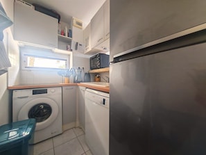 Eine kompakte Küche mit Waschmaschine, Geschirrspüler und einem Edelstahl-Kühlschrank.