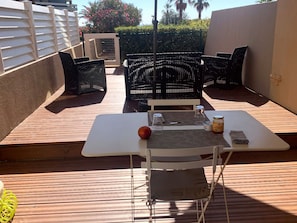 Eine Terrasse mit Tisch, Stühlen und einem kleinen Garten.