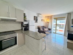 Eine moderne Küche mit Granit Arbeitsplatten, einem eingebauten Ofen und einer Essecke mit einem kleinen Tisch und Stühlen.