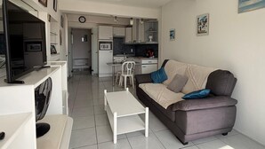 Ein modernes Wohnzimmer mit einer Couch, einem Fernseher und einem Essbereich mit Stühlen.
