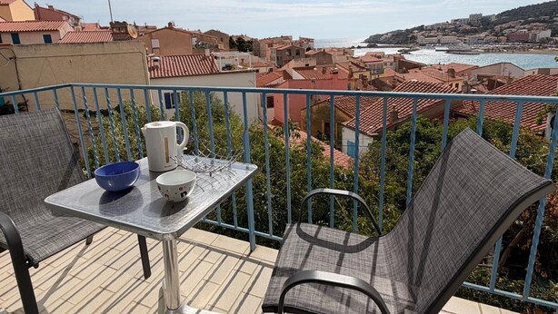 Ein Balkon mit Tisch, Stühlen und Blick auf eine Küstenstadt.