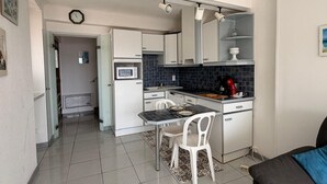 Eine kleine Küche mit Essbereich, einer Mikrowelle, einer Kaffeemaschine und einer Uhr an der Wand.