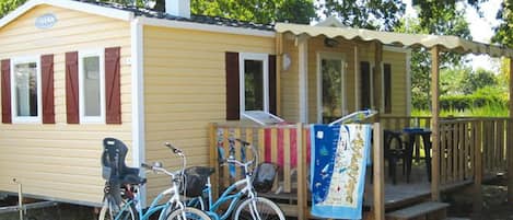 En liten, envåningsbyggnad med en överbyggd veranda och en cykel parkerad utanför.