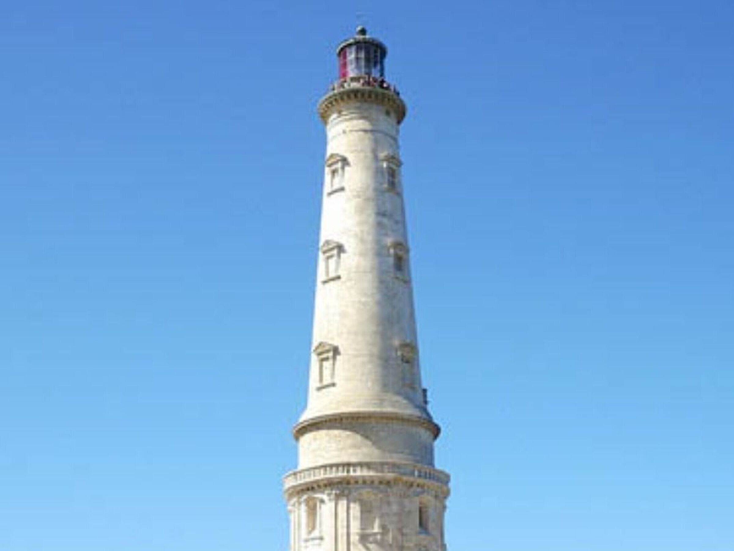 Uma torre alta e cilíndrica com janelas e topo vermelho.