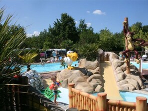 Ein Wasserpark mit Pool, Rutschen und einer Maskottchen-Figur.