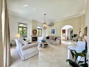 A spacious living room with a fireplace, a sofa set, a coffee table, and a dining area. - Algarve Stunning Villa by Homing (Faro)