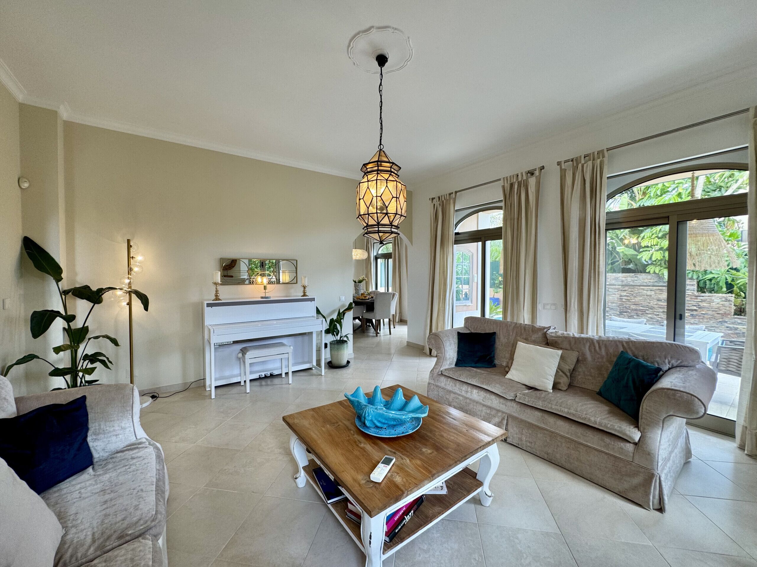 A living room with a sofa, coffee table, and a fireplace. There is a dining area with a table and chairs.