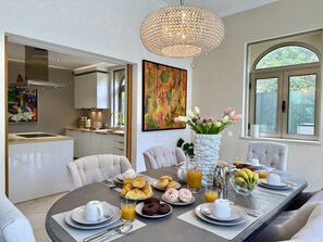 A modern dining area with a round table set for breakfast, a chandelier, and artwork on the walls. - Algarve Stunning Villa by Homing (Faro)