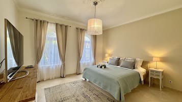 A bedroom with a bed, bedside tables, a desk, and a television.
