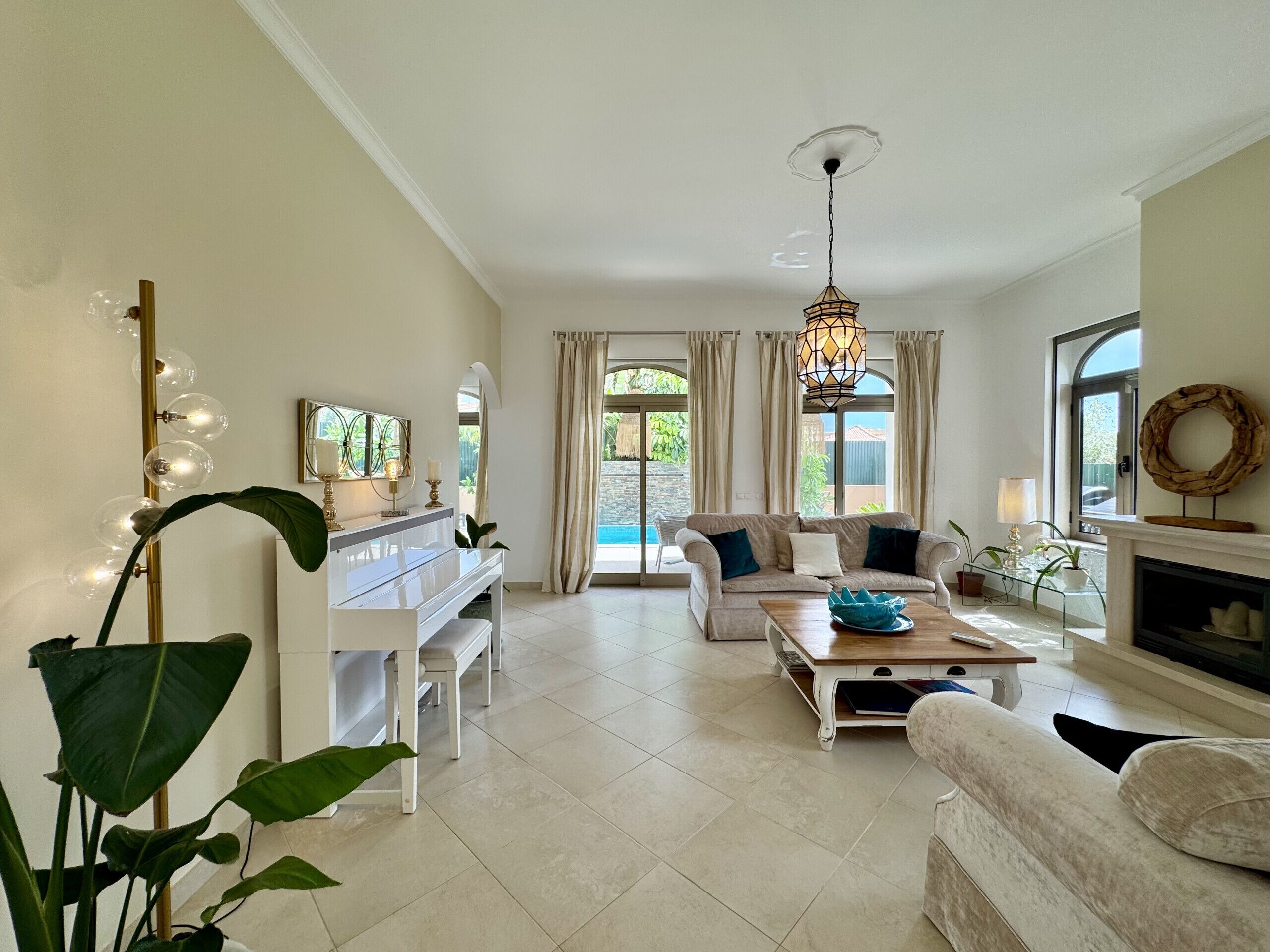 A spacious living room with a piano, a sofa, a coffee table, and a fireplace.
