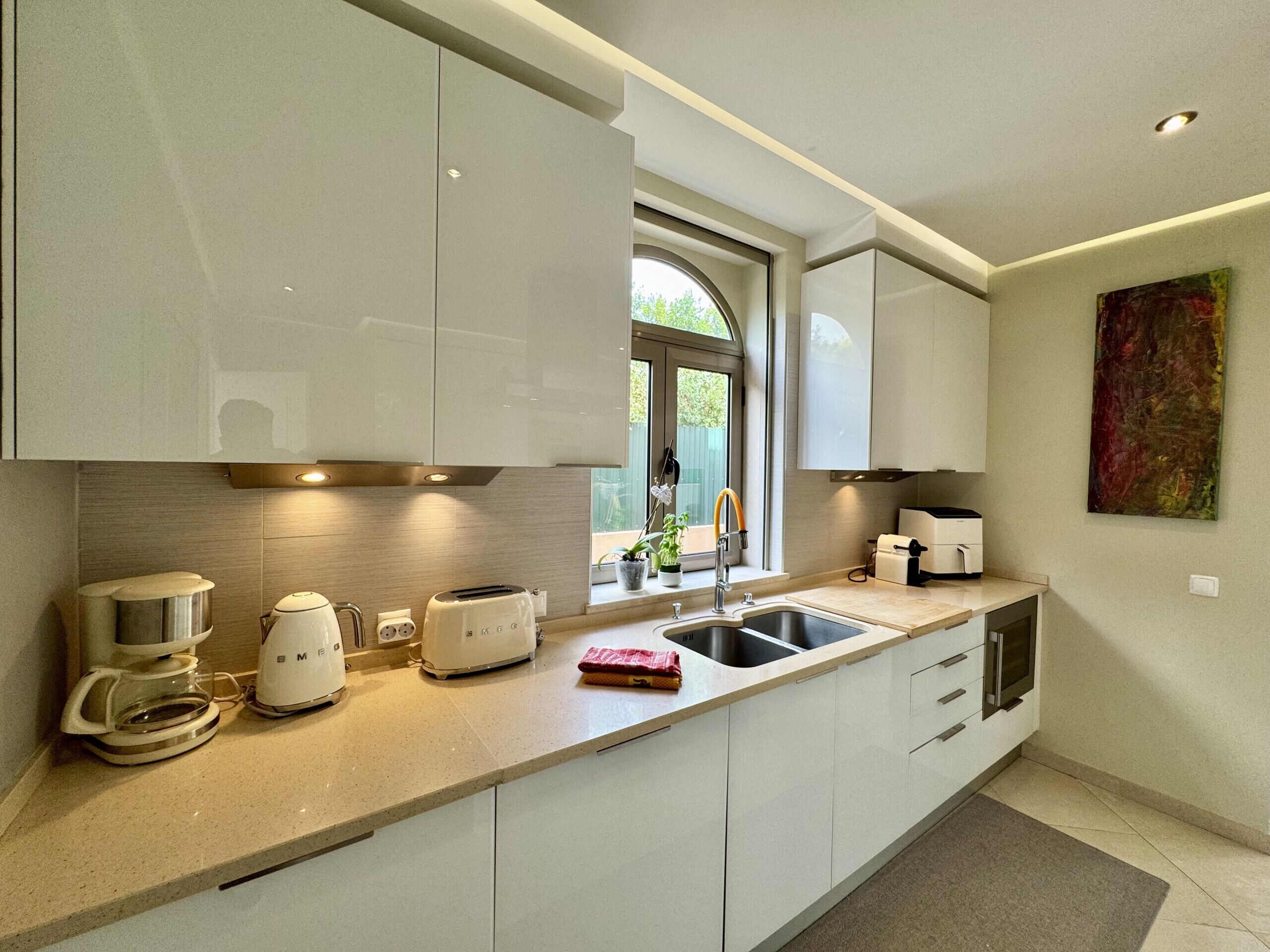 A modern kitchen with white cabinets, a built-in oven, a coffee maker, and a toaster.