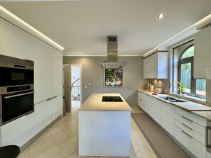 Una cocina moderna con electrodomésticos integrados, una isla central y un amplio ventanal que proporciona luz natural.