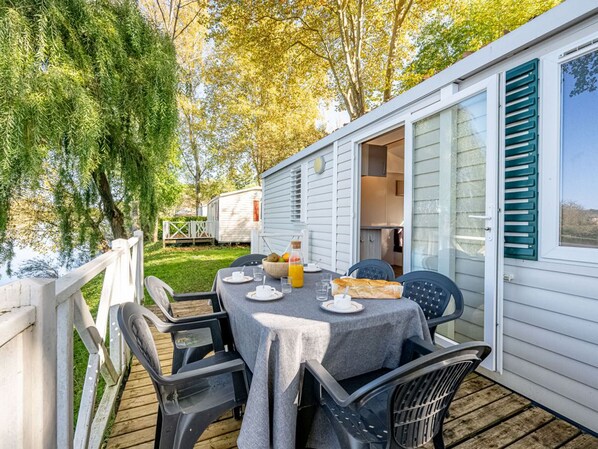 Eine Terrasse mit einem Tisch für zwei Personen, Stühlen und Blick auf ein Mobilheim.