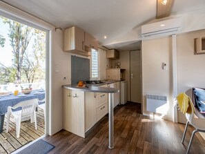 Eine moderne Küche mit Holzausstattung, einem Gasherd und einem Essbereich mit Tisch und Stühlen.
