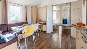 Una habitación moderna y bien iluminada con sofá, mesa de comedor y kitchenette.