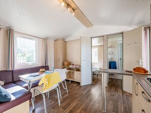 Ein modernes, helles Zimmer mit einer Couch, einem Esstisch und einer Küchenzeile.