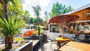Eine Terrasse im Freien mit Holzdeck, einem Tisch, Stühlen und einem Modell eines Oldtimers.