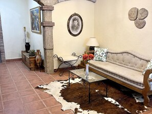 A living room with a sofa, a glass coffee table, a cowhide rug, a wooden cabinet, a stone pillar, a framed portrait, and a lamp. - Spacious apartment - 8 guests, heart of Riudoms (Riudoms)