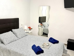 A neatly arranged bedroom with a bed, pillows, a bedside table with a lamp, a mirror, and a tray with cups and a book. - Spacious apartment - 8 guests, heart of Riudoms (Riudoms)