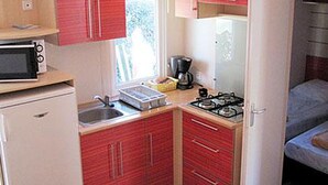 Een kleine keuken met een magnetron, kookplaat en koelkast.