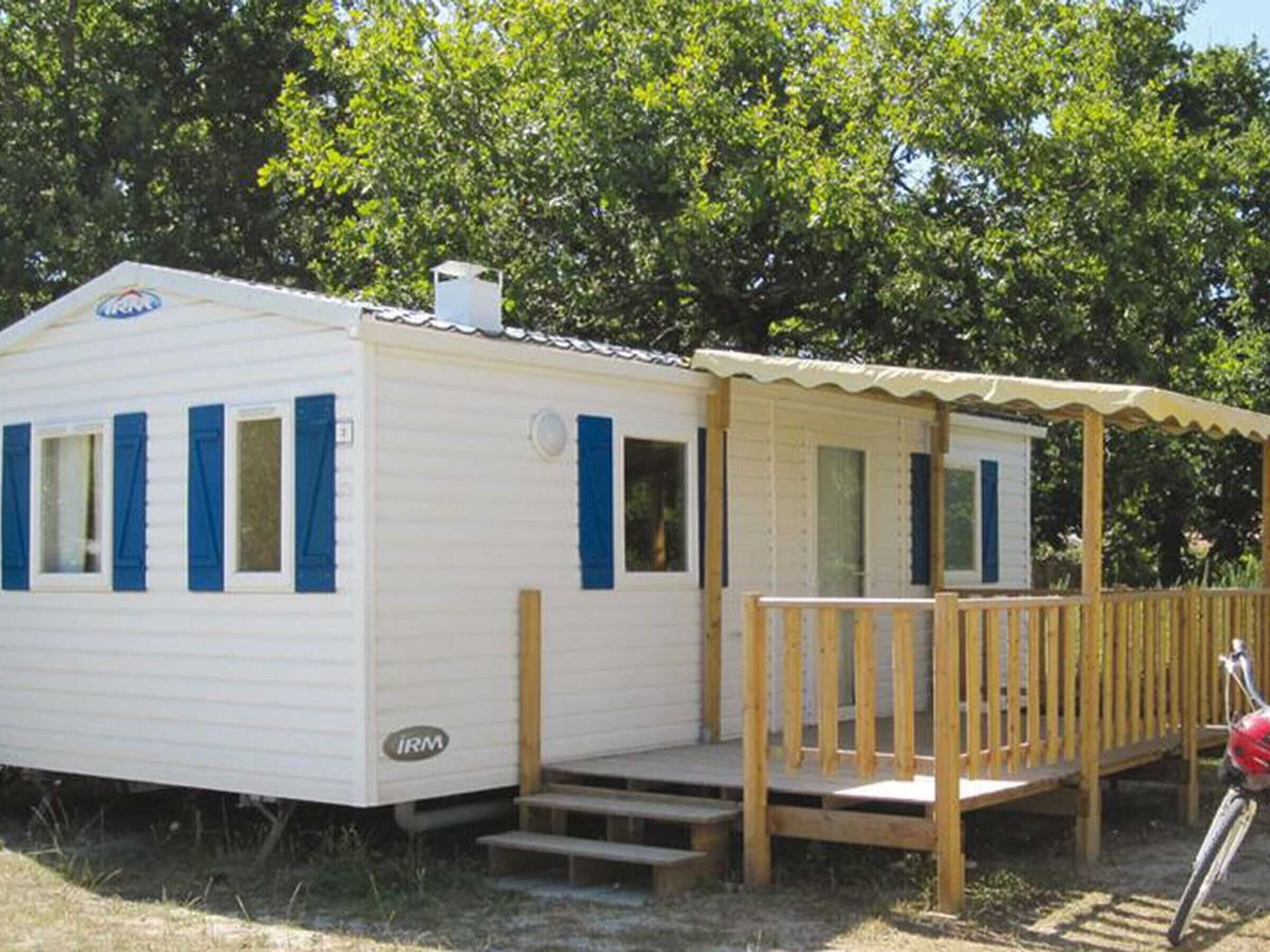 Une maison mobile avec un porche, un vélo et une petite terrasse.