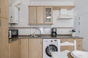 Une cuisine compacte équipée d’un lave-linge, d’une machine à café et d’un grille-pain.