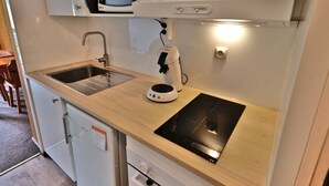 Kompakti keittiö, jossa on pesuallas, mikroaaltouuni, kahvinkeitin ja induktioliesi.