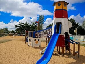 Ein Spielplatz mit Rutsche, Klettergerüsten und einem Turm.