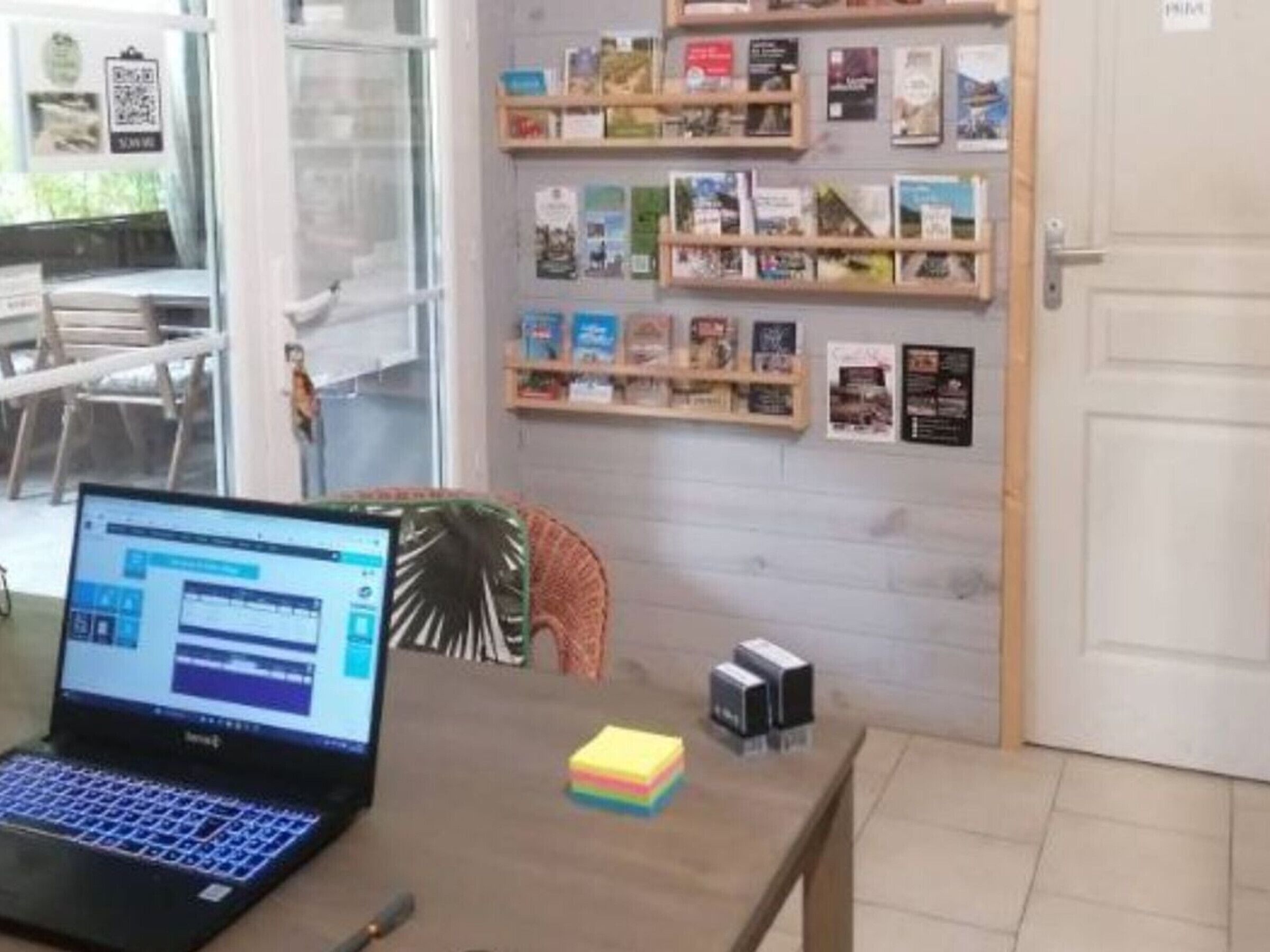 Un ordinateur portable sur une table, une bibliothèque remplie de livres et une porte.