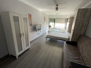 Ein Zimmer mit einem Bett, einem Kleiderschrank, einem Deckenventilator, einem Fernseher und einem Balkon mit Blick.