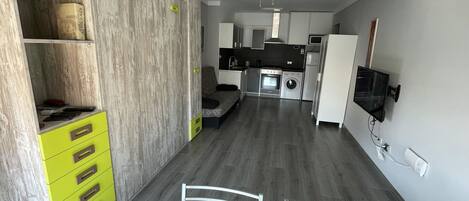 Une cuisine compacte avec un coin repas, un ventilateur de plafond et un lave-linge encastré.