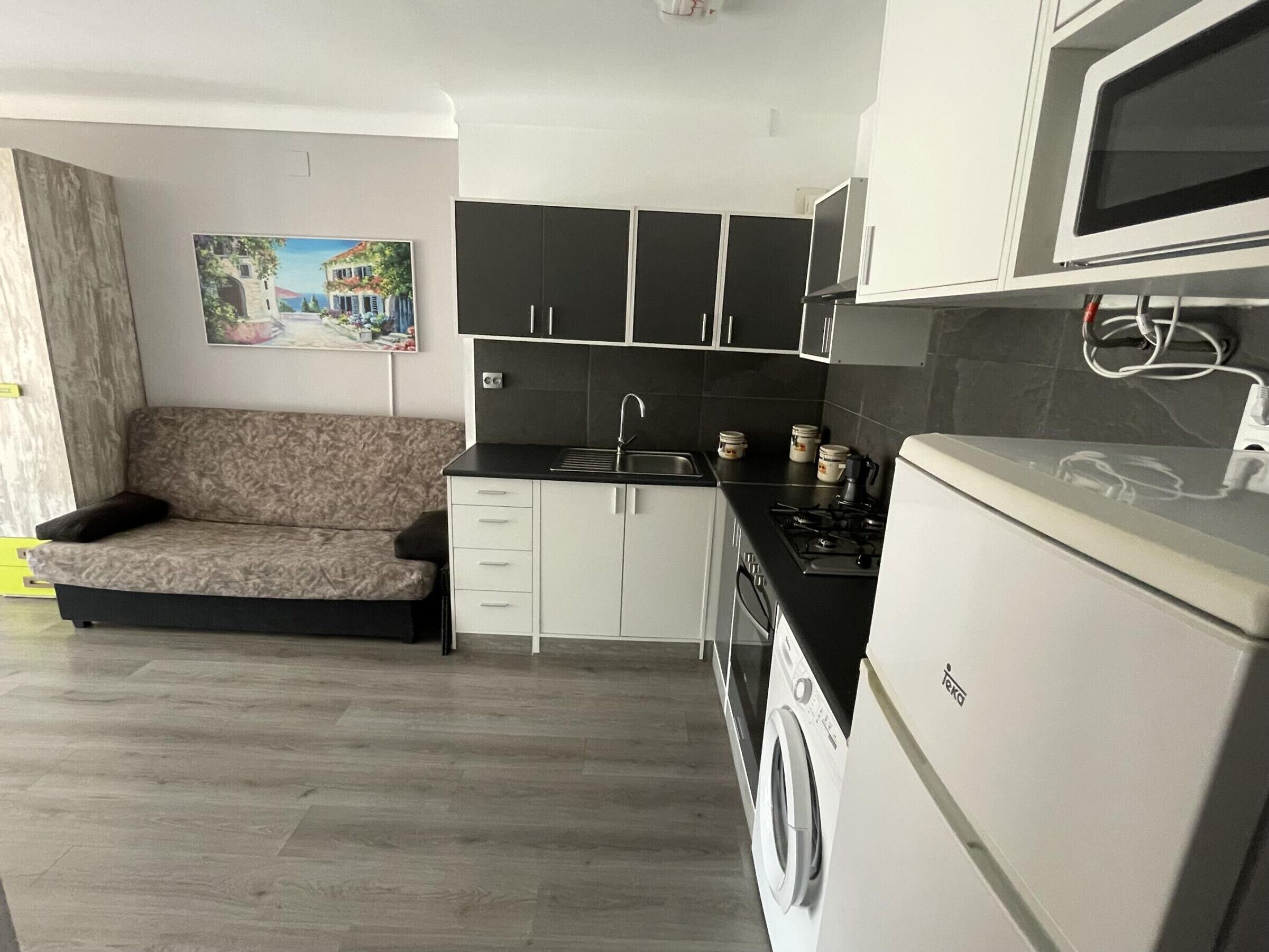 Una cocina compacta con sofá, lavadora y microondas.