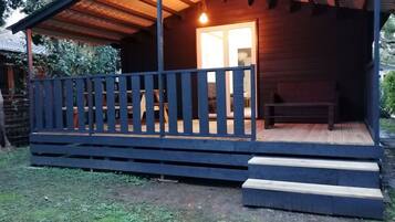 Une cabane en bois avec une véranda, des marches et un banc.