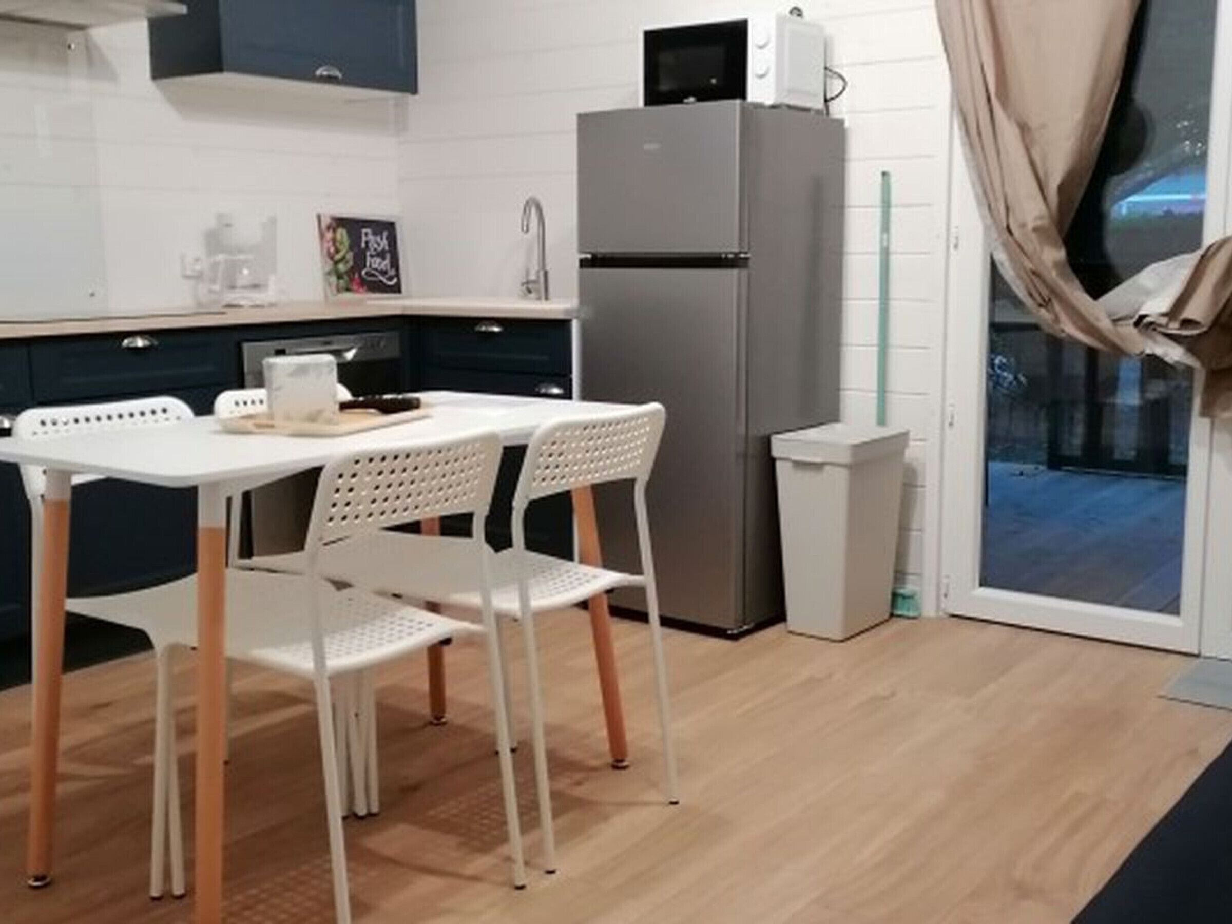 Une cuisine compacte équipée d’un réfrigérateur, d’un four à micro-ondes et d’un coin repas avec une table et des chaises.